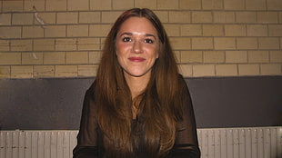woman wearing black dress shirt near brown wall