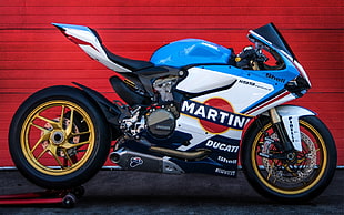 white and blue Ducati sport bike near red wall HD wallpaper
