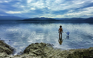 toddler holding fish net in the seashore