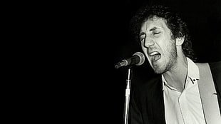 man in black suit jacket and white dress shirt singing