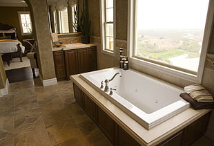 white ceramic bathtub near window