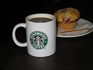 white ceramic mug with Starbucks print beside cupcake on white ceramic plate