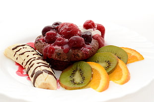 chocolate cookie with raspberry, banana, kiwi and orange slices on plate