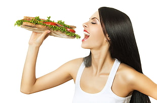 woman wearing white tank top holding sandwich
