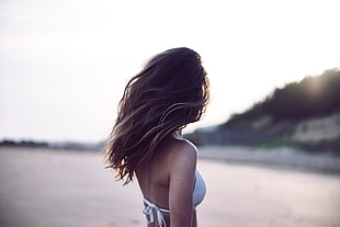 selective focus photography of a woman in white drawstring bikini top facing the wide view under white sky