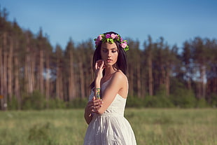woman in white sleeveless dress standing near forest trees under blue clear skies at daytime