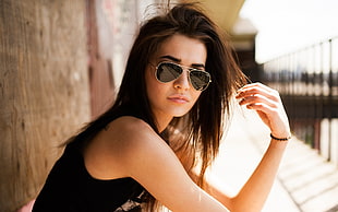 woman and black sleeveless top wearing gold-framed aviator sunglasses