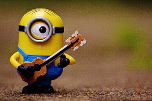 Minion plastic toy holding brown guitar