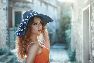 woman wearing gray sunny hat and orange sleeveless blouse