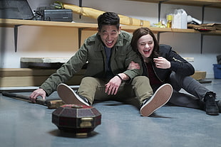 laughing man and woman wearing jacket sitting on floor
