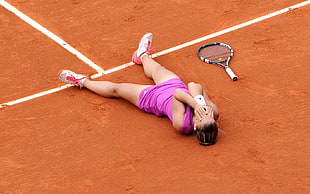 female tennis player lying down on tennis court during daytime