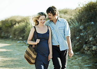woman wearing black spaghetti-strap dress standing beside man wearing blue chambray western shirt during daytime HD wallpaper