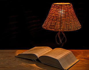 brown wicker pendant table lamp and reading book on brown wooden table top