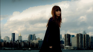woman wearing black coat standing in cityscape photograph
