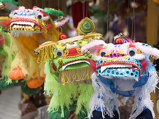 close photo shot on three white, green, and yellow Lion Dance puppets HD wallpaper
