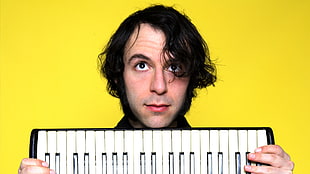 man holding white and black electronic keyboard