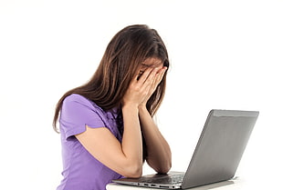 woman in purple polo shirt covering her face using her hands