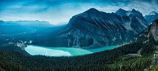 landscape photo of mountain near trees and body of water at daytime