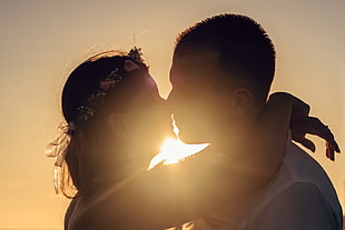 woman wearing flower headdress kissing man in white shirt