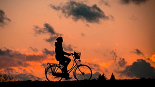 person's silhouette riding step-through frame bike during golden hour HD wallpaper