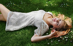 woman wearing white square-neck mini dress lying on green grass