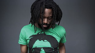 man wearing a black and green crew-neck shirt with dreadlocks