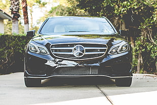 black Mercedes-Benz car parked on pavement near green trees