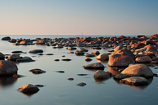 rocks on body of water under blue sky HD wallpaper