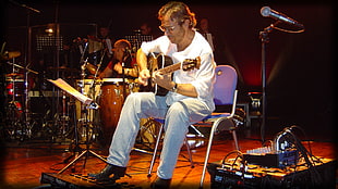 man holding acoustic guitar while sitting