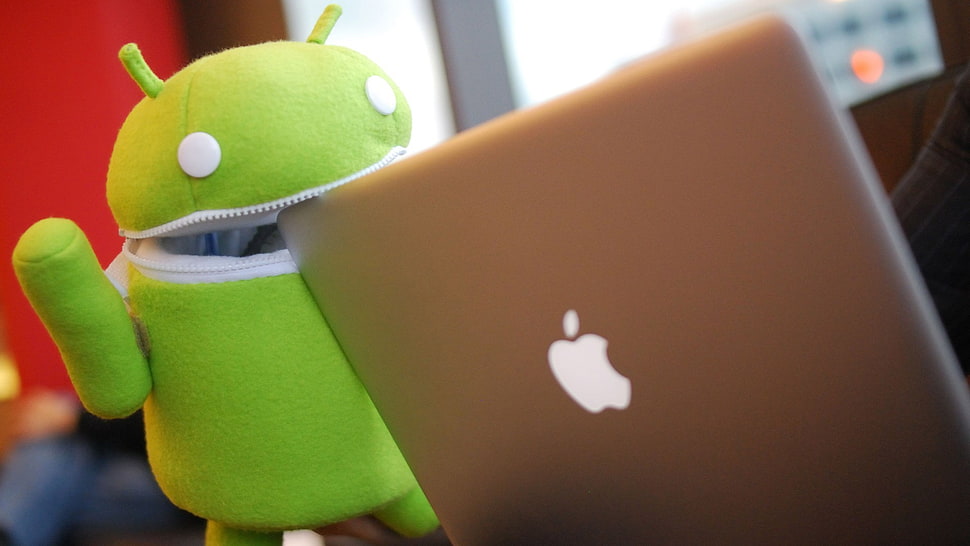 green Android plush toy biting silver MacBook HD wallpaper