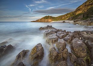 landscape photography of seashore near brown and green cliff during day time, anglesey
