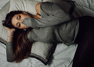 woman in gray long-sleeved shirt lying on bed