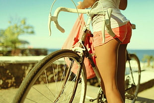 woman wearing pink short shorts holding road bike