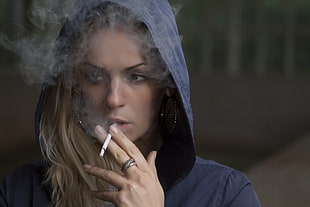 smoking blonde haired woman wearing navy-blue hoodie