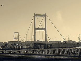 grayscale photo of metal suspension bridge