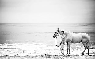grayscale photo of horse and woman near sea