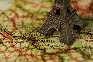 silver-colored Eiffel Tower miniature on Paris map