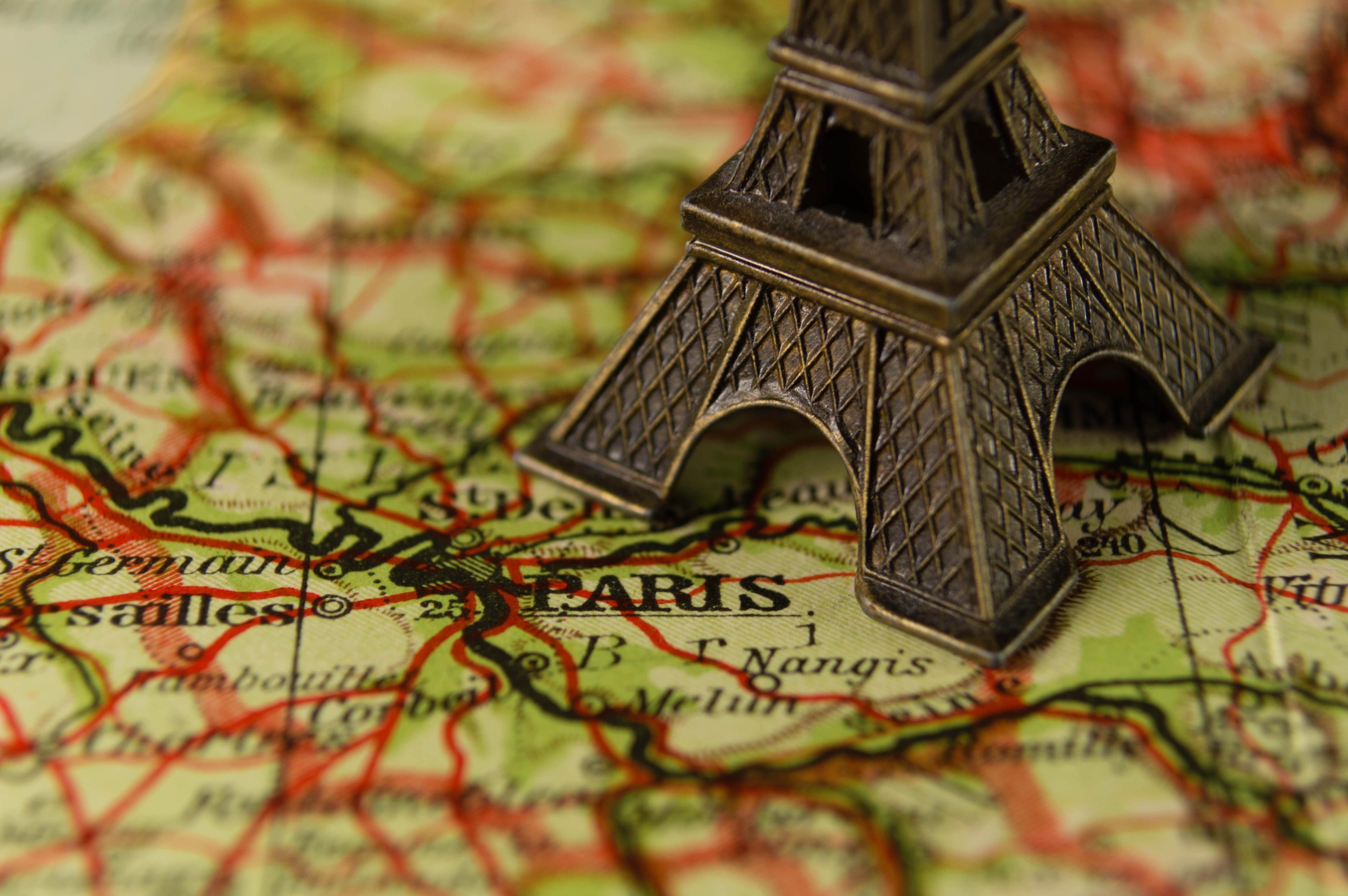 silver-colored Eiffel Tower miniature on Paris map