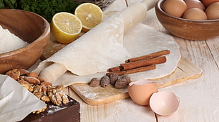 brown rolling pin near egg shells and lime fruits
