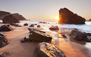 timelapse photo of stones beside shore during sunset