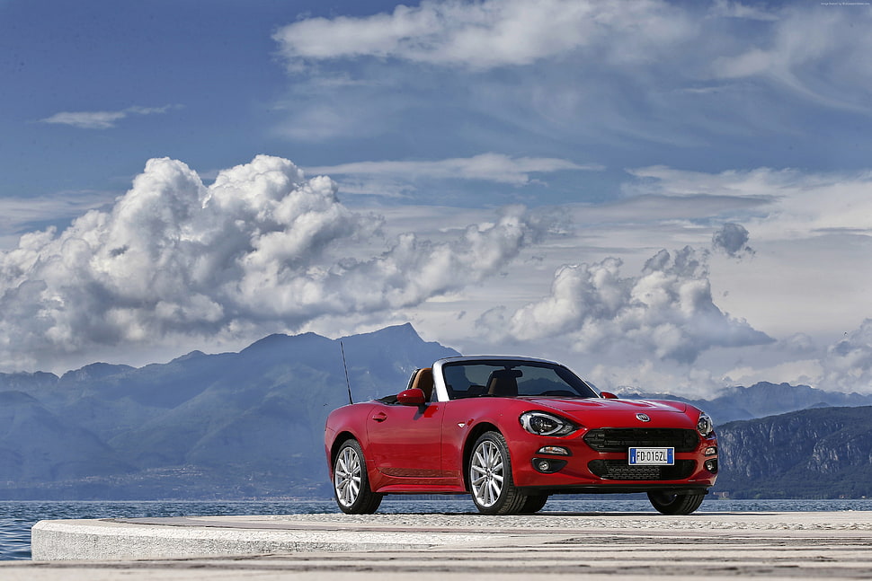 photography of red convertible coupe on asphalt road under cloudy sky HD wallpaper