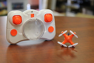 orange and white quadcopter with remote control