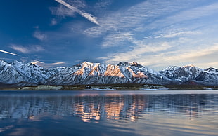 shallow focus photography of snow covered mountains near body of water during daytime