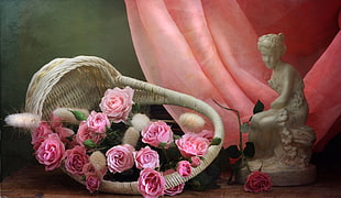 basket of pink and red Roses beside figurine painting