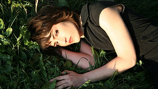 woman in black top lying on green grass during daytime