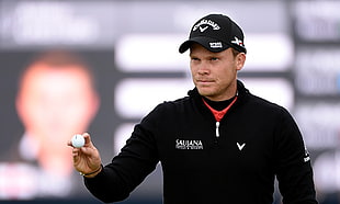 man holding golf ball wearing black Callaway fitted cap and black jacket