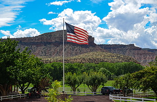US flag on white pole with mountain on background