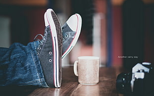 depth of field photography of person wearing blue jeans and black-and-white low top sneakers