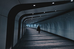 woman walking inside empty tunnel wearing cape