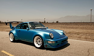 blue Porsche 911 with blue spoiler on asphalt road